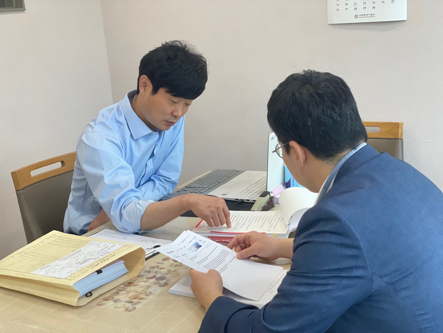 사무실 책상에서 서류를 보며 상담하는 변호사와 의뢰인